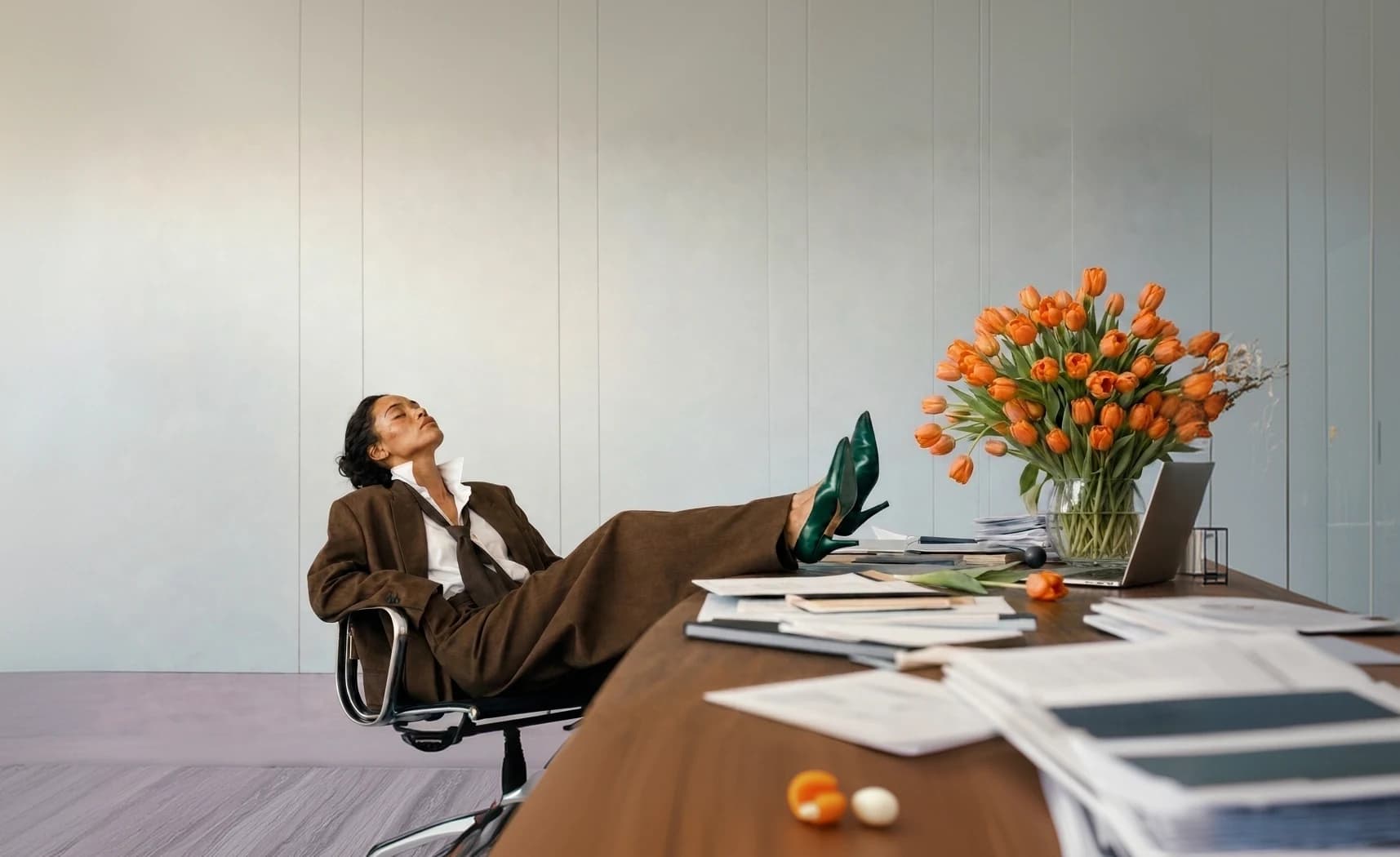 A creative director relaxing at a desk beside orange tulips and campaign materials
